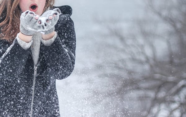 Image of a woman blowing snow out of her hands
