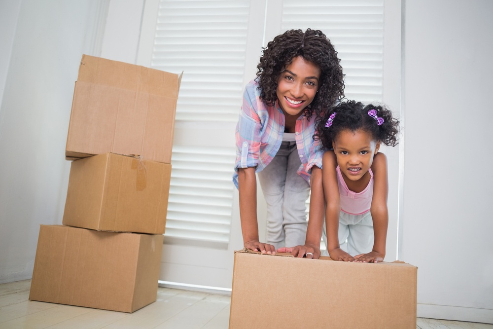 Cute daughter unpacking moving boxes with her mother in their new home