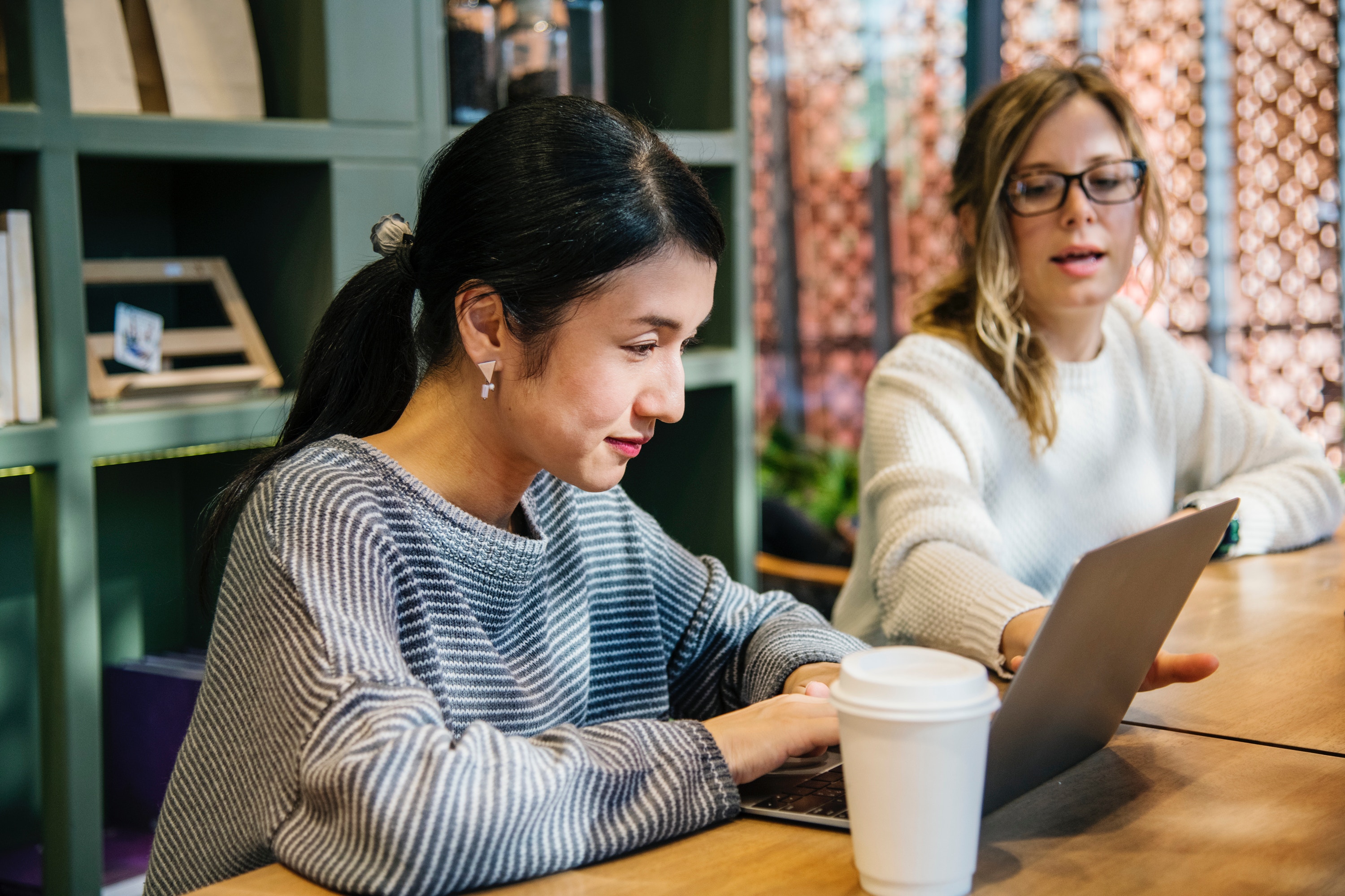 A photo of two women sitting at a table with a laptop