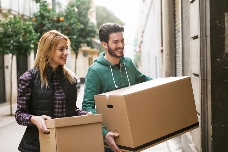 photo of a young couple carrying boxes